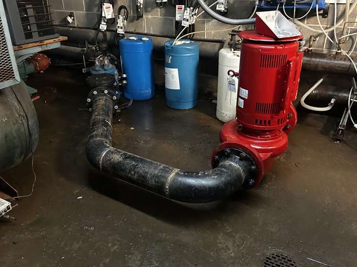 Chilled-water pump, suction piping, and cylinders in a commercial mechanical room.