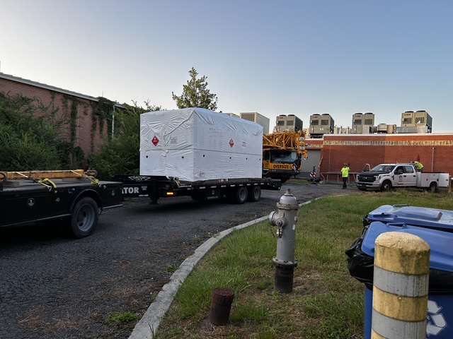 Wrapped commercial chiller on a trailer with a crane staged for a lift.