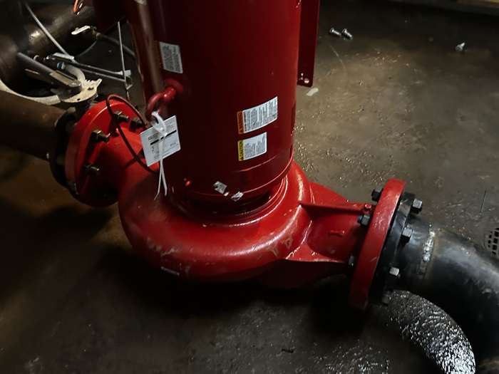 Red chilled-water pump and flanged piping in a commercial mechanical room.