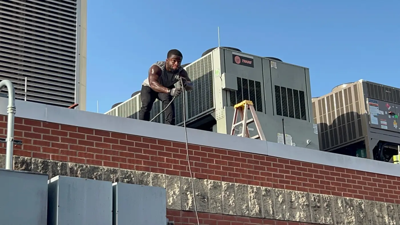 Technician working at a Trane rooftop air conditioner on a commercial roof in New Orleans