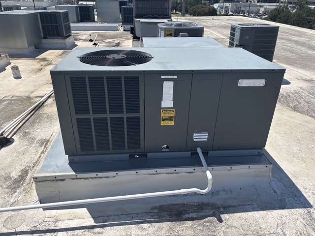 Packaged rooftop unit on a curb with a condensate line, the equipment type replaced on New Orleans commercial roofs.