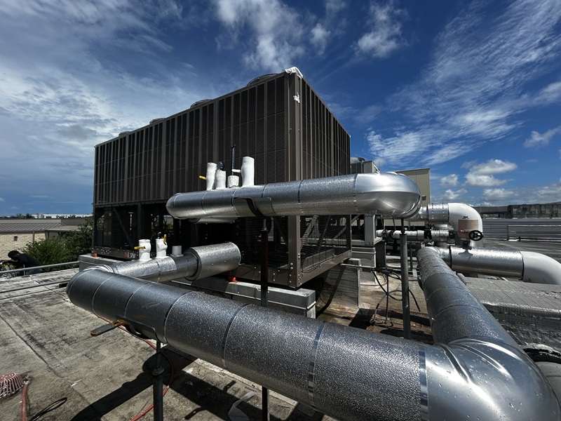 A cooling tower with insulated condenser-water piping on a commercial rooftop.