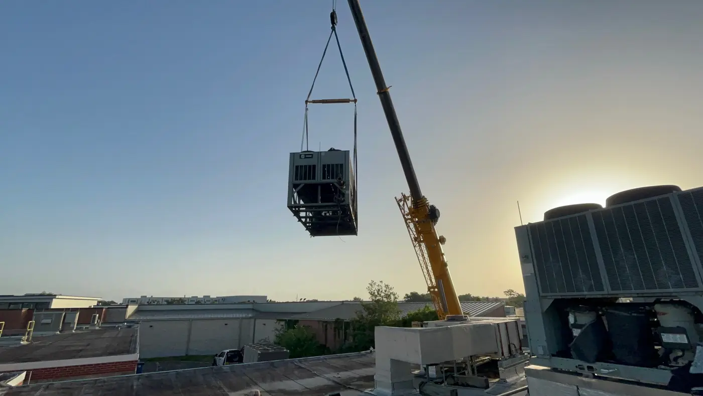 Crane lifting a commercial rooftop HVAC unit off a New Orleans roof