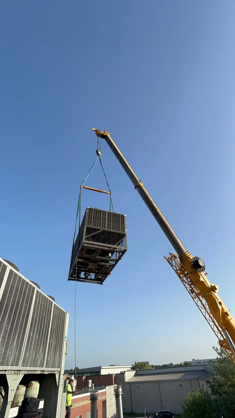 Crane setting a commercial packaged rooftop unit