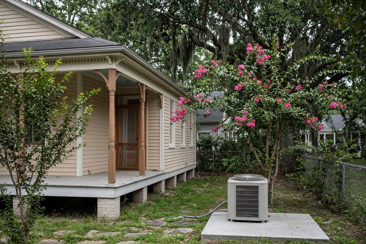 Raised Gulf Coast cottage with an outdoor condenser on a concrete pad under live oaks